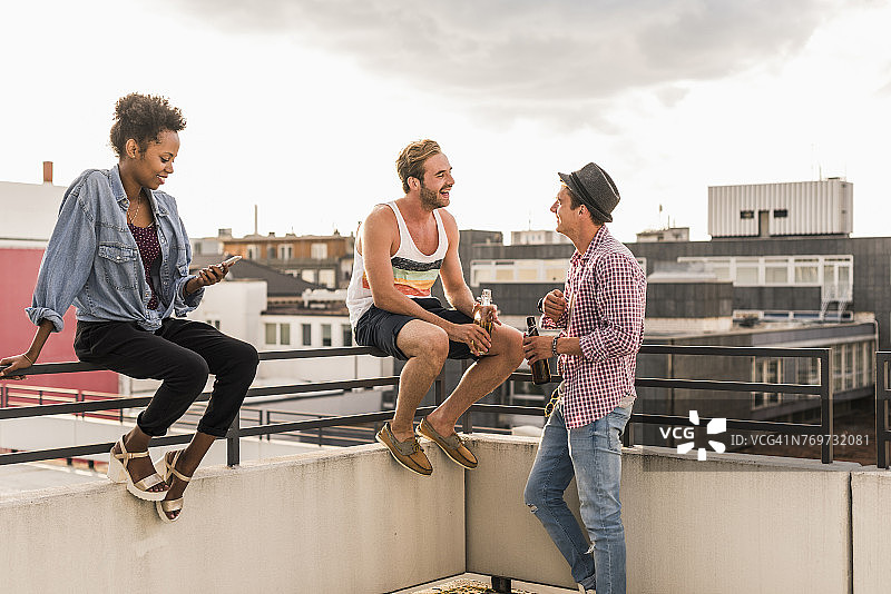 三个朋友在屋顶派对上社交图片素材