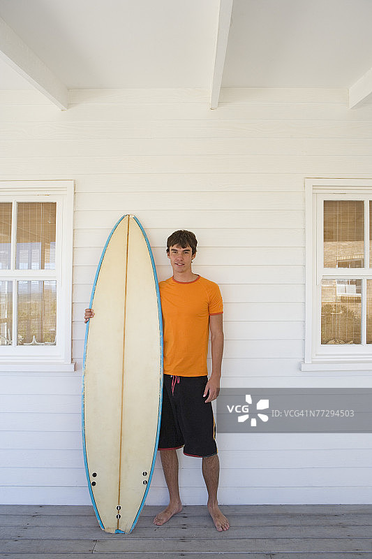 在海边的房子里拿着冲浪板的男人图片素材