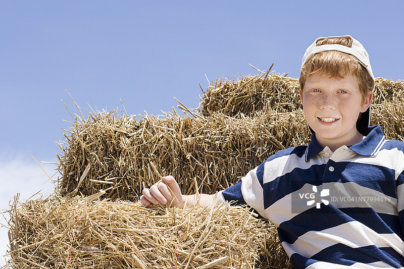 一个小男孩坐在装干草的拖车上的肖像图片素材