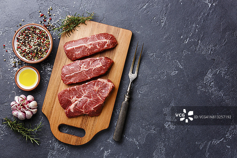 生鲜肉上刀尖的牛排放在木板上，背景为黑色图片素材