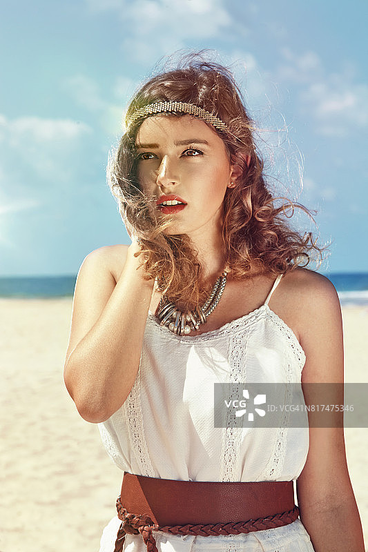 一个风和日丽的日子，美丽的长发少女站在海滩上图片素材