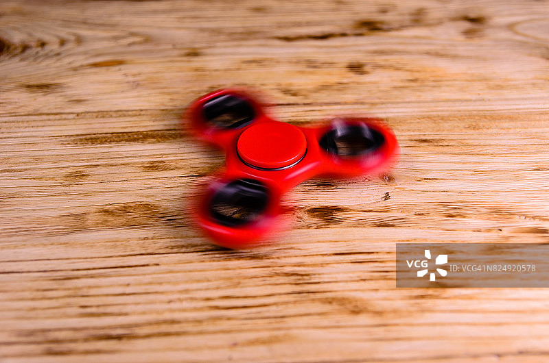 红色的旋转玩具在木桌上旋转图片素材