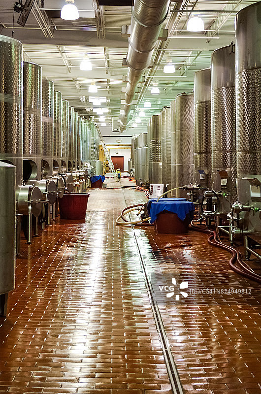 现代化的酿酒厂有大型金属铝发酵罐或酒桶，用于酿酒葡萄和干净的瓷砖地板图片素材
