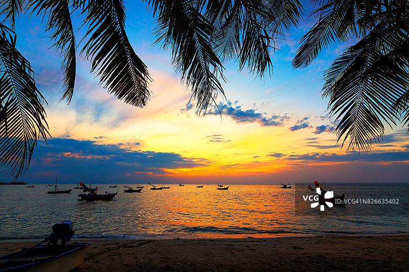 在印度洋的热带岛屿上，棕榈树的黑色剪影和令人惊异的多云的日落天空。椰子树与美丽和浪漫的日落。哥道是泰国最受欢迎的旅游目的地。图片素材