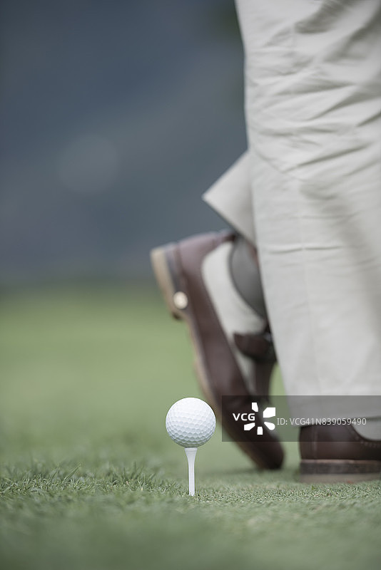优雅的高尔夫球手站在球座上靠近高尔夫球图片素材