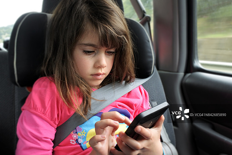 小女孩在车里玩手机图片素材