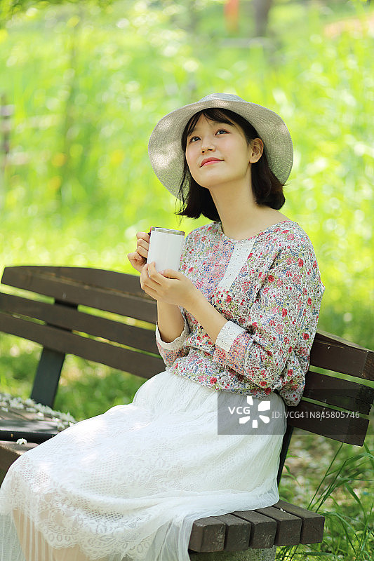 在公园里拿着一杯咖啡的女人图片素材