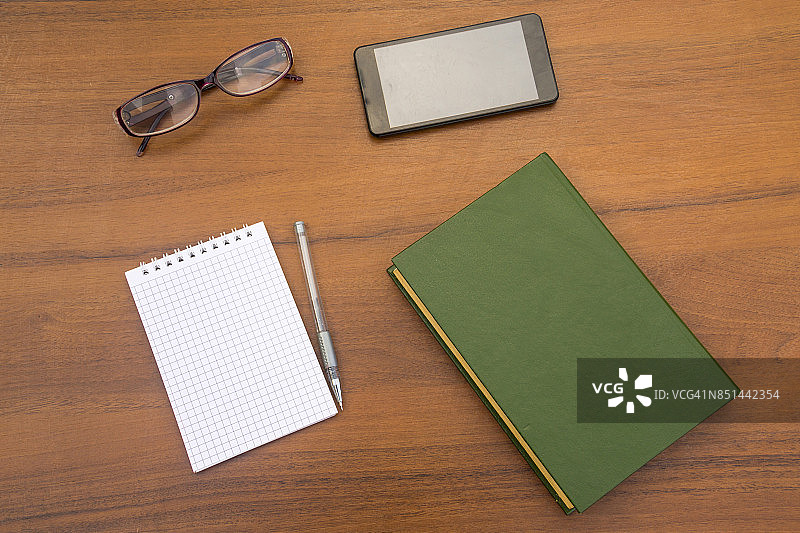 书，记事本，笔，眼镜和智能手机放在木桌上图片素材