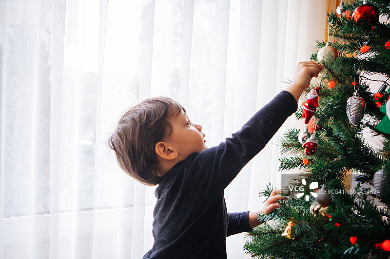可爱的小男孩装饰圣诞树图片素材