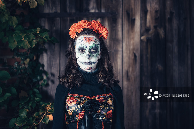 少女戴着诡异的万圣节面具站在旧谷仓前图片素材