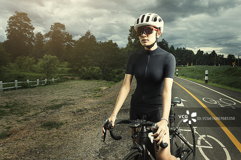 亚洲健康的自行车女孩戴头盔骑自行车和锻炼自行车在短跑跑道和开放的道路图片素材