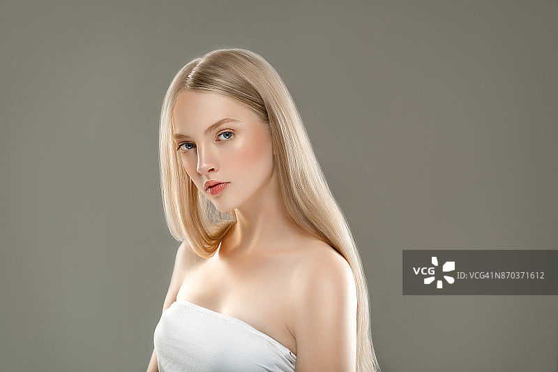 美丽的女人面部肖像美丽的皮肤护理概念与长金发。灰色背景下美丽发型的模特图片素材