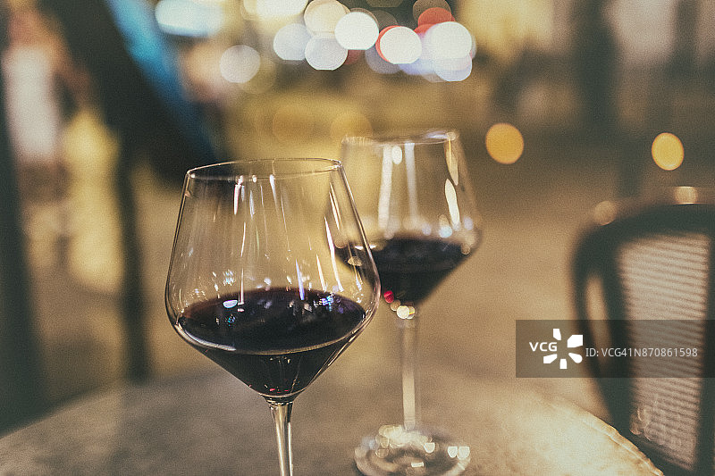 在巴黎，人行道上一个café酒吧的桌子上放着两杯红酒。图片素材