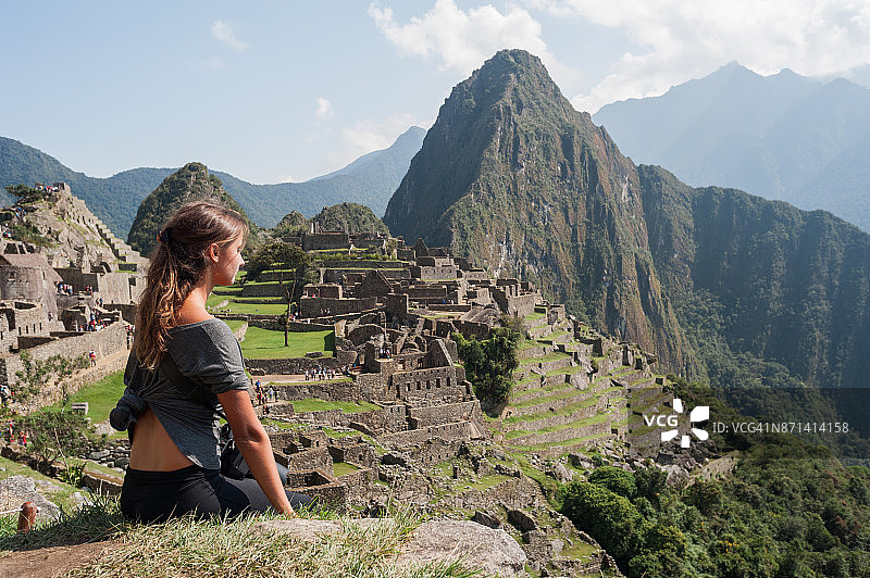 一名年轻女子站在秘鲁古城马丘比丘的悬崖上。图片素材