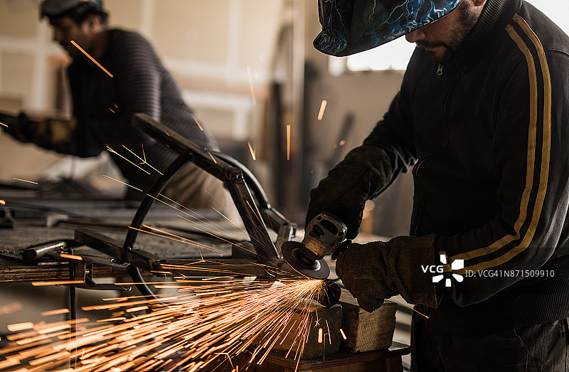 金属工人在车间工作时磨铁。图片素材
