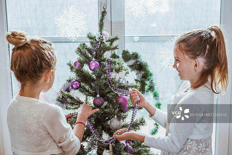 两个小女孩微笑着装饰圣诞树图片素材
