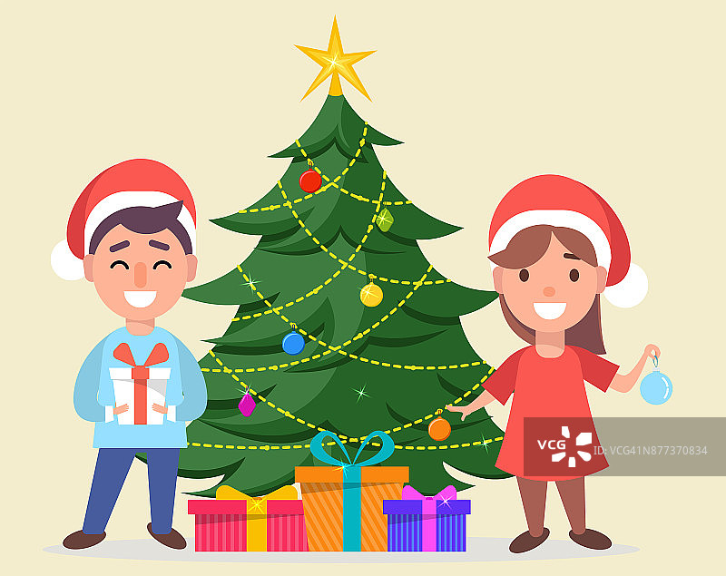 男孩和女孩戴着圣诞老人的帽子站在装饰圣诞树旁图片素材