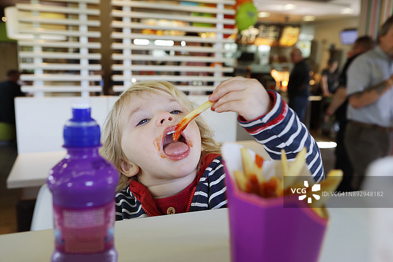 蹒跚学步的孩子在餐厅吃快餐图片素材