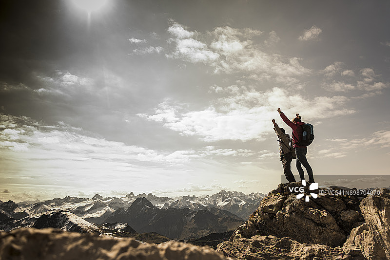 德国，巴伐利亚，奥伯斯特多夫，两个徒步旅行者在高山风景的岩石上欢呼图片素材