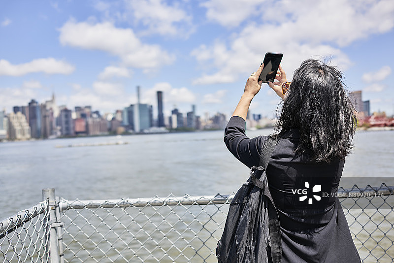 一名女性正在拍摄纽约市的天际线图片素材