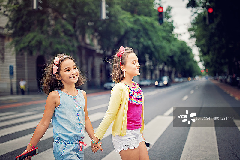 快乐的小女孩们正在人行横道上过马路图片素材