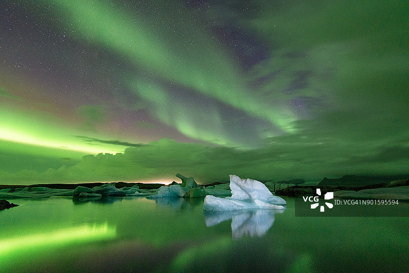 在强烈的北极光下，冰岛的Jokulsarlon冰山及其在Vatnajokull冰川泻湖上的反射景观图片素材
