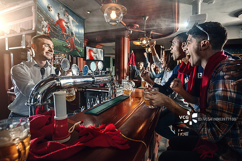 朋友们在看足球比赛，在酒吧喝啤酒图片素材