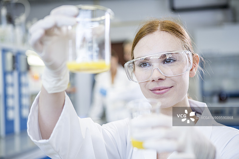 实验室里的科学家举着两个盛满液体的烧杯图片素材
