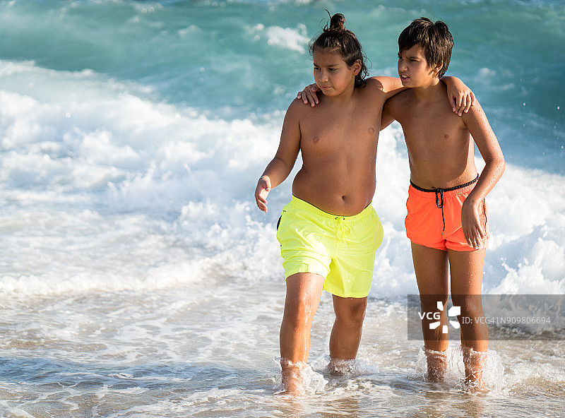 男孩子们一起在海滩上用海浪泼水图片素材