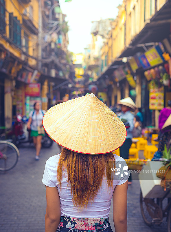 越南河内街头一个戴着锥形帽子的越南妇女的后视图图片素材