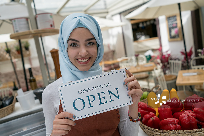 穆斯林企业主在一家餐馆举着营业标牌图片素材