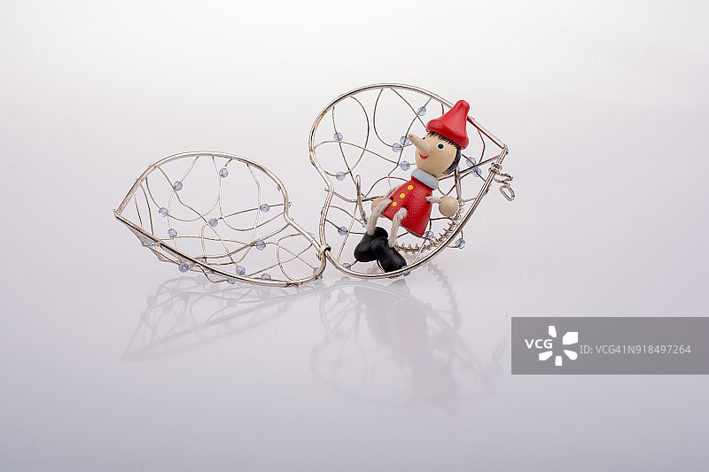 皮诺曹玩偶坐在一个心形的笼子上图片素材
