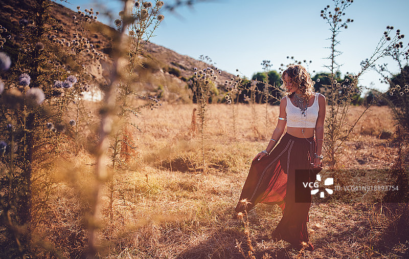 美丽的波希米亚女人穿着红裙子在野外放松图片素材
