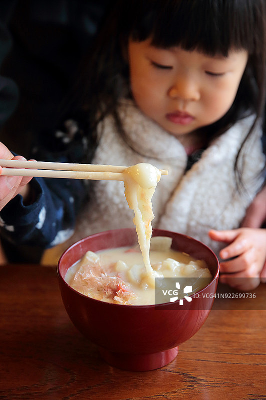 女儿和父亲在吃日本新年菜肴，叫做Zouni图片素材