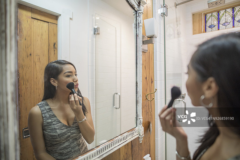 年轻女子在浴室镜子前化妆图片素材