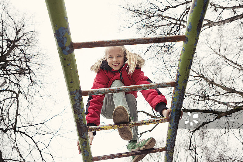 儿童在操场上的金属攀爬架上保持平衡图片素材