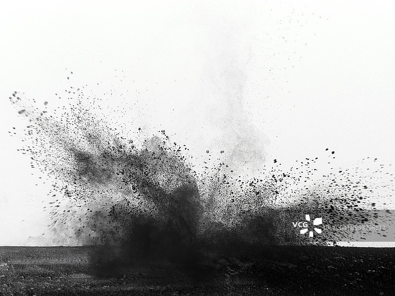 爆炸是由一团黑色和白色背景的彩色粉末颗粒撞击而成。图片素材