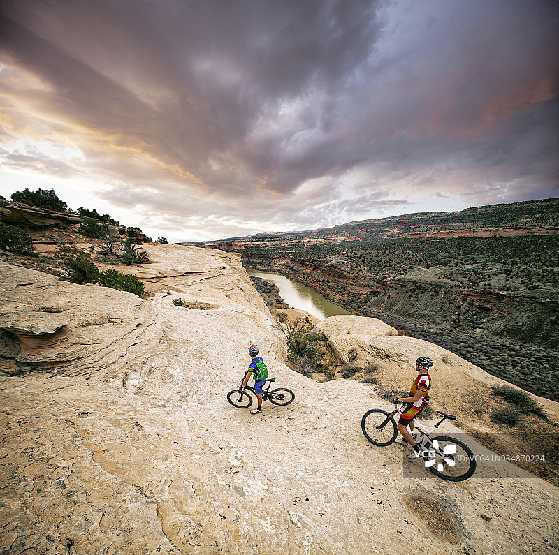两名男子在极端的砂岩岩架上骑山地车图片素材