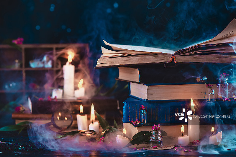 一堆古董书和蜡烛的梦幻场景。魔法研究和烛光阅读的概念。黑暗的静物与复制空间。图片素材