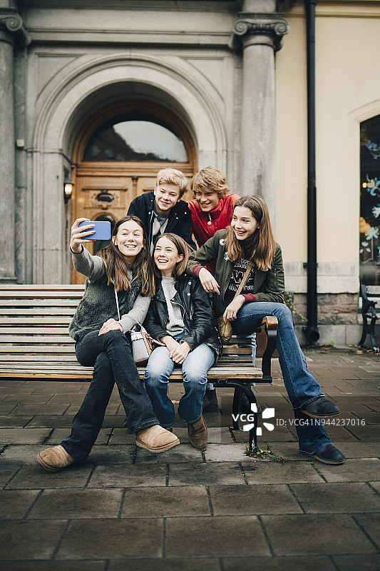 全长女孩通过手机自拍与朋友在城市图片素材