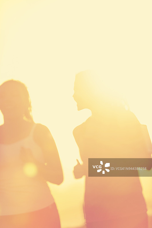两个女人在日落时在公园里跑步。图片素材