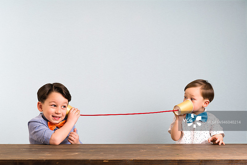两个孩子正在用纸杯当电话图片素材