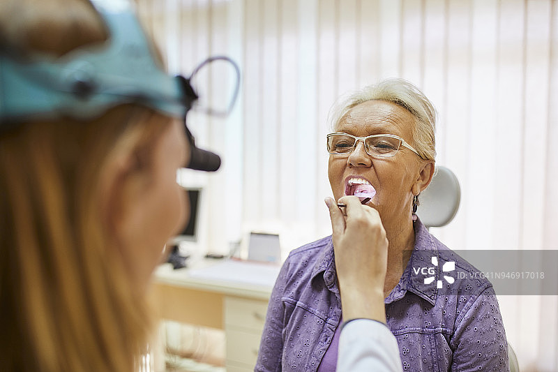 耳鼻喉科医生正在检查一位老年妇女的口腔图片素材