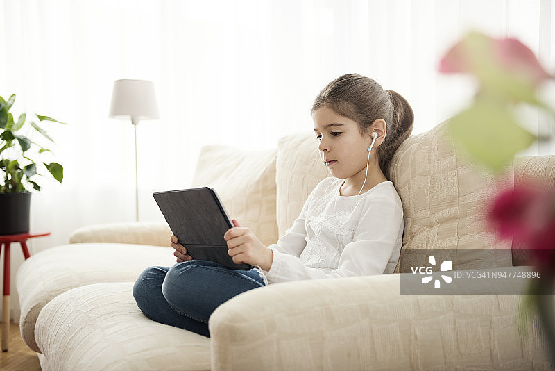 小女孩在家里玩电子平板电脑图片素材