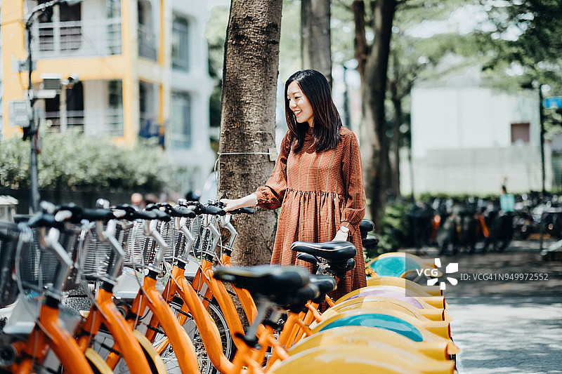 美丽的亚洲女孩在市中心租用共享单车图片素材
