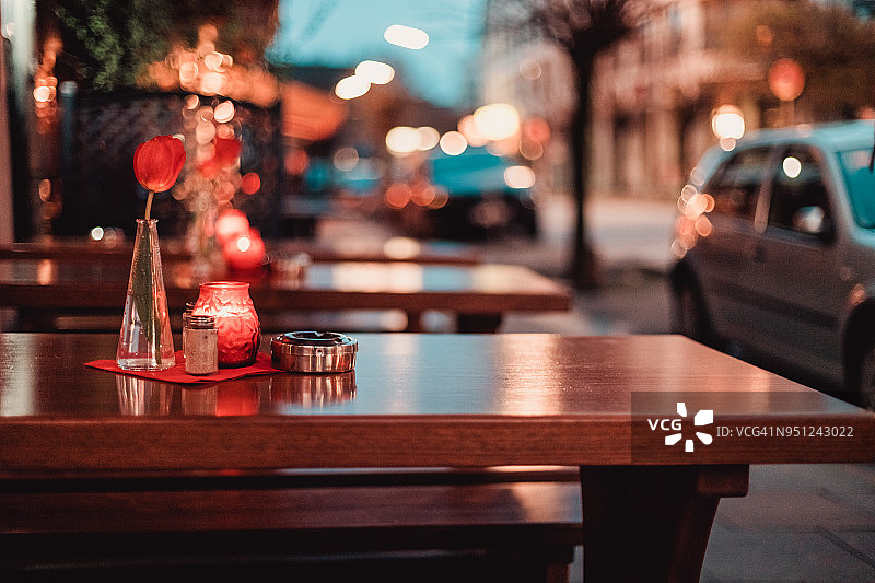 餐厅的餐桌上摆放着郁金香、蜡烛和烟灰缸，街灯模糊不清图片素材