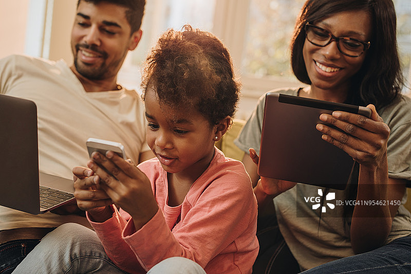 幸福的非裔美国家庭在家里使用无线技术。图片素材