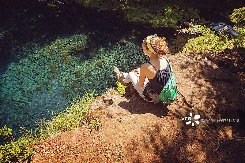 高角度的女性徒步旅行者坐在岩石对湖图片素材