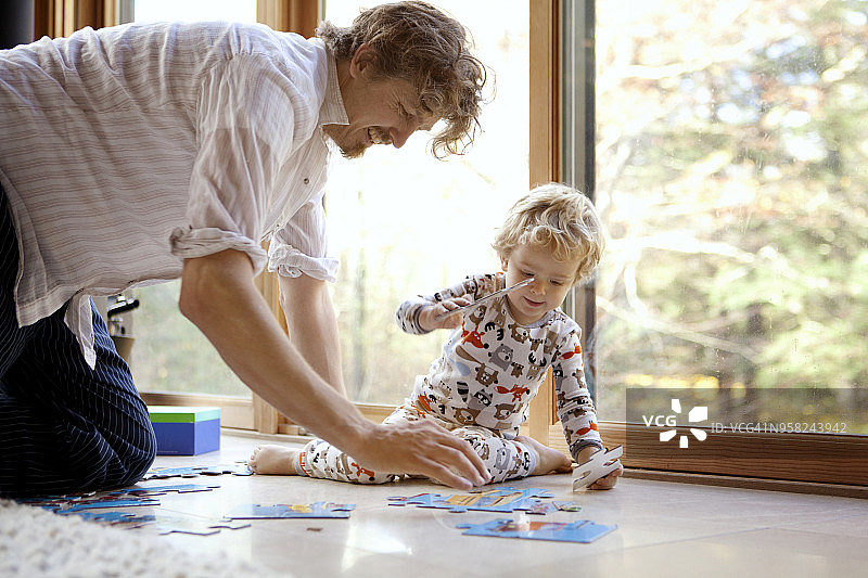 父亲和儿子在家里安排拼图游戏图片素材
