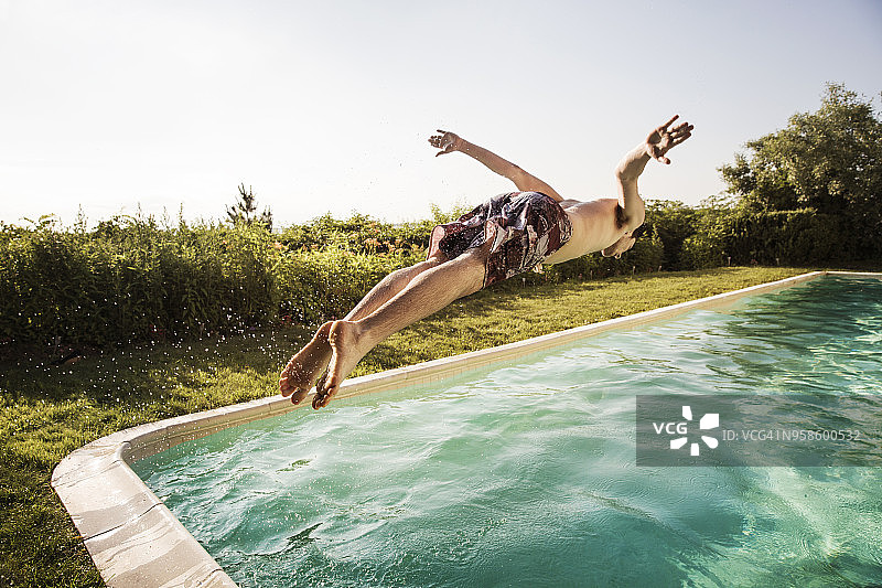 晴朗的天空下，一名男子跳入游泳池图片素材